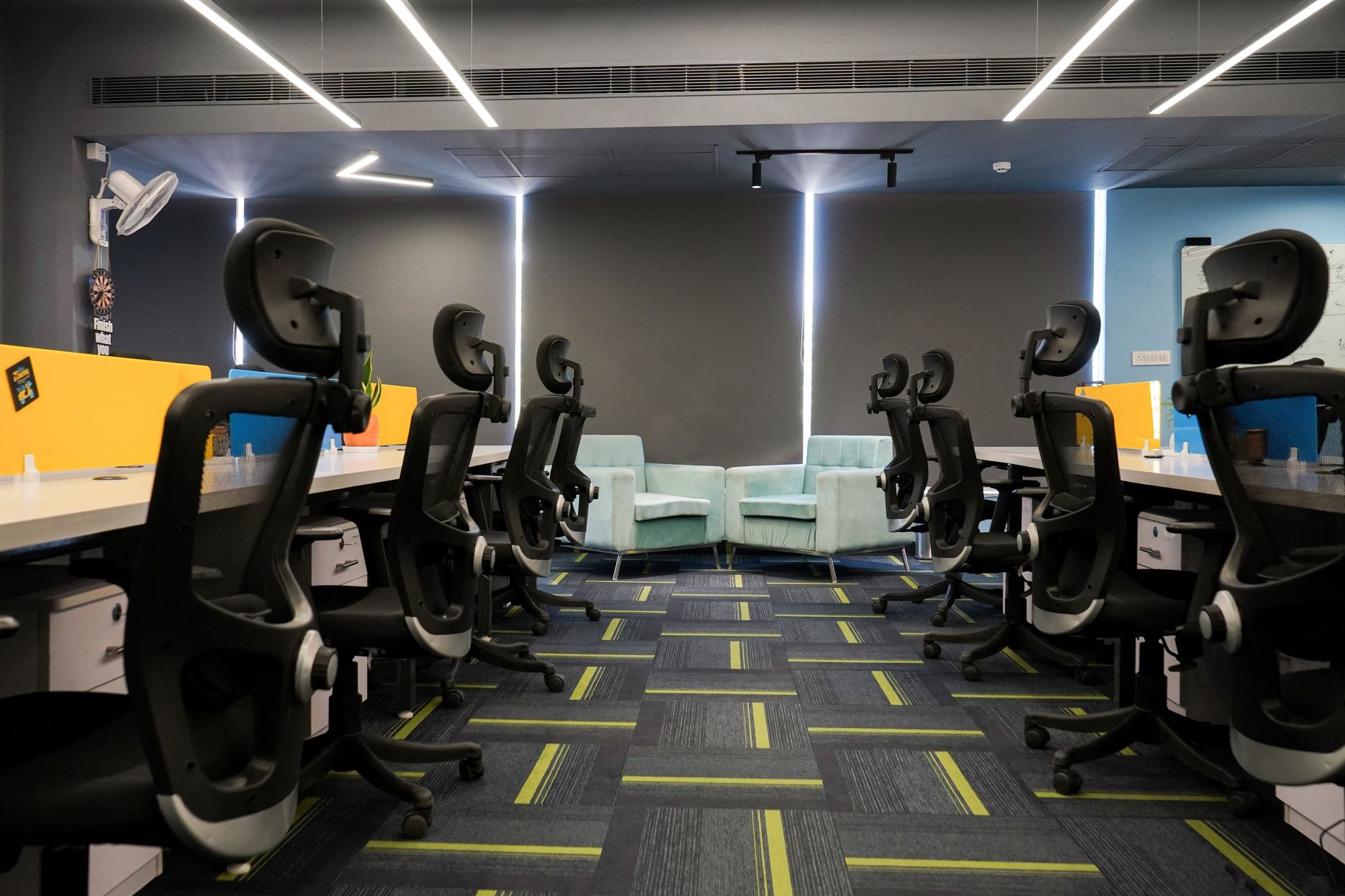 Studio desks with chairs facing a small pairing of armchairs